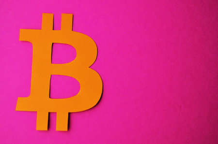 Orange bitcoin sign on a pink background with a copy space. Cryptocurrency in the style of...