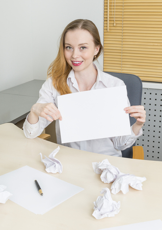 Woman in office holds sheet of paper with copy spaceの写真素材
