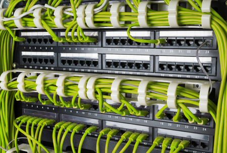 Rows of green network cables connected to router and switch hub in server room at internet data...