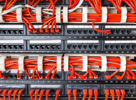 Rows of red network cables connected to router and switch hub in server room at internet data center