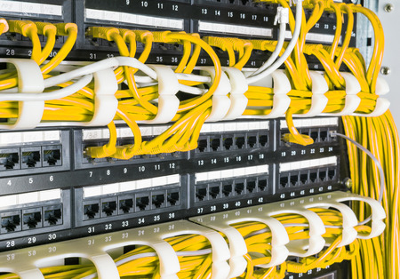 Close up of yellow network internet cables, patch cords connected to black switch, router in data...