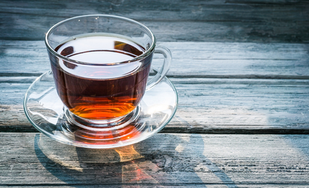Transparent cup of black tea and dry twig herb on wooden background with copy space. Tonedの写真素材