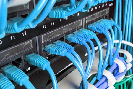 Server rack with green internet patch cord cables connected to patch panel in server room