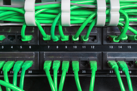 Server rack with green internet patch cord cables connected to black patch panel in server room horizontalの写真素材