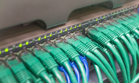 Light blue patch cord internet cables connected to black switchの写真素材