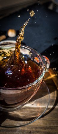 Cup of tea with splash on dark wooden background. Verticalの写真素材