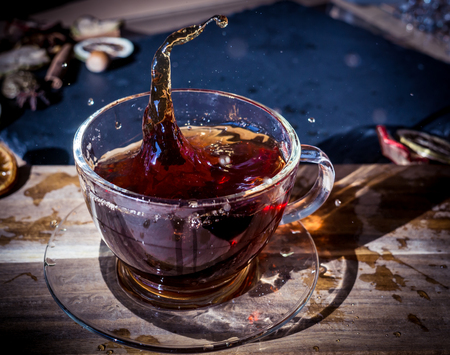 Cup of tea with splash on dark wooden backgroundの写真素材