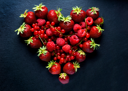 Berries heart with redcurrant, strawberry and raspberry on black backgroundの写真素材