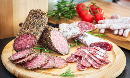 Assorted sliced italian pork salami on wooden plateの写真素材