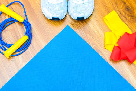 planning sports at home. On the yoga mat there is an empty place, next to it are an elastic band for...