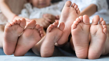 baby bare legs in the frame. barefoot brother and sister. three. wrinkled. fun together.