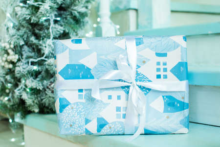 on the steps a gift near the Christmas tree. blue, mint shades. New Year holiday.