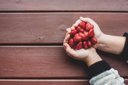 children's hands are holding many red glittering hearts. Valentine's Day. Flat lay, top view. space for text, space for copy. Love, February 14. The concept of love, trust, faith, help.の写真素材