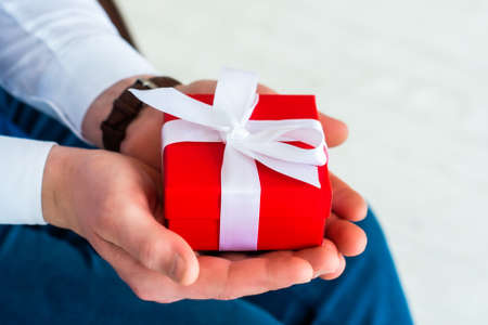male hands are holding a gift. Office delivery service. Cropped shot of business man with red box....