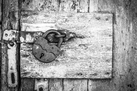 rusty lock on a texture of old, metal, iron, black and white door, which the old paint flaking. the passage is closed. locked. place for textの写真素材