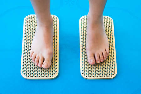 Women feet are standing on a board with sharp nails, Sadhu Board. yoga practice. pain, trial, health. blue yoga matの写真素材