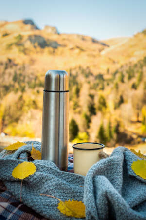 picnic, autumn forest. against the background of mountains retro , mug and scarf. orange leaves. fall has comeの写真素材