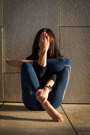young woman practicing yoga in the park. in the rays of the sun at sunset. pose raised her legs....