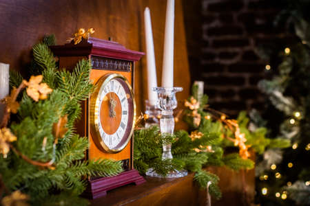 happy new year and christmas. the clock shows midnight. there is a golden garland on the tree. candles, bokeh and lightsの写真素材