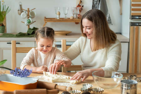 girl and woman cook at home. in a kitchen, a child stirs flour, knead the dough on the table by hand.の写真素材