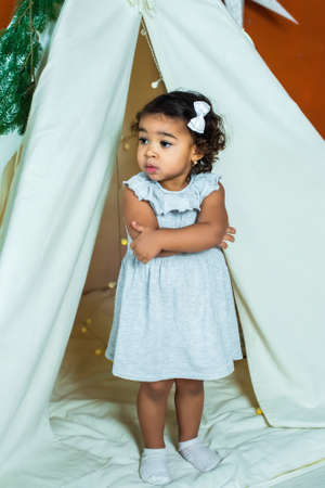 black, african-american girl play in a tent, wigwam. kid is sad and scared. baby is alone and upset.