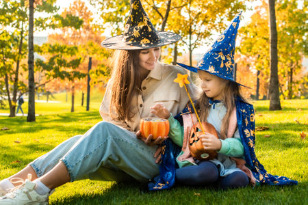 mom and daughter in costumes and witch hats. in the park together. trick or treat. Happy Halloween