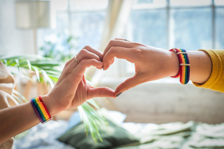 gay pride concept. female hands making a heart sign with gay pride LGBT rainbow flag wristband.の写真素材