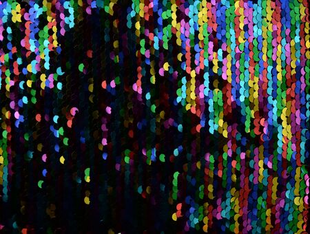 Sequins close-up macro. Abstract background with multicolor sequins on the fabric. Texture scales of round rainbow sequins with color transition.の写真素材