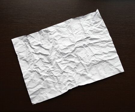 White Abstract crumpled paper on dark wooden table. Top view of old Paper textures background for...