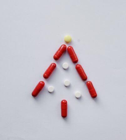 Christmas tree from Pharmacology assorted medicine pills, tablets and capsules. Different colors tablet on white background. Health care. Top view with Copy spaceの写真素材
