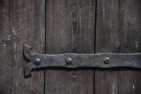 Rural background from wooden planks with knots in vertical parallel pattern texture. Dark Wood wall facade, antique door fragment with metal rusly loop. With copy space for textの写真素材