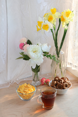 A mug of tea, a cup of corn and a cake on a sunny table, a bouquet of spring flowers for mood, diet food and a healthy lifestyle in the village, a beautiful morning in the villageの写真素材