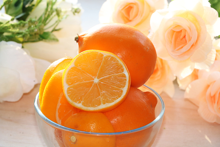 A lemon on a sunny table. A bouquet of cream roses in the background creates a good mood of a spring morning and a good day.;の写真素材