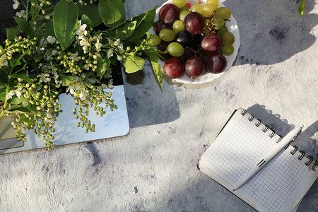 Computer, notebook and bird cherry on a bright table., View from above. Break at work, rest and flowers for relaxation before a hard day's workの写真素材