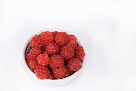 Red raspberries in a cup on a white isolated background, selective focus, copy space .. Natural...