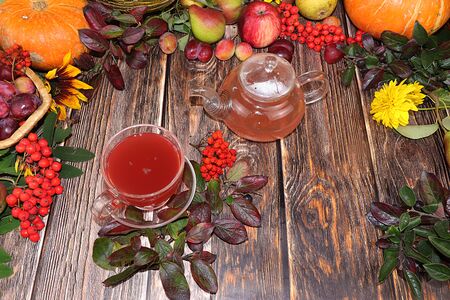 Cup of hot tea on an autumn wooden table with vegetables and fruits on a wooden table, flat lay, copy space. Coziness and comfort at home in the cold autumn, harvesting and approaching Thanksgiving.の写真素材