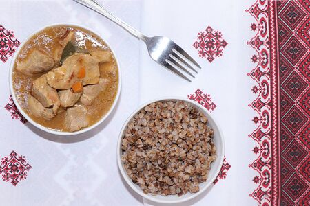 Boiled buckwheat flakes with stew with carrots in a bowl on a light table. Traditional Russian organic food, diet food, selective focus, top viewの写真素材