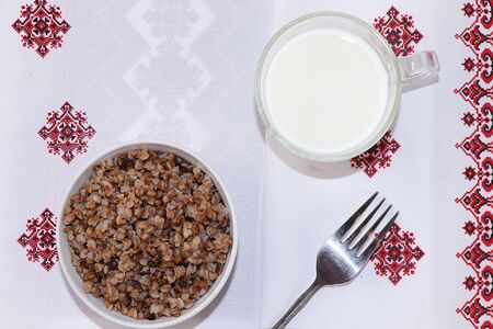 Boiled buckwheat cereal with milk in a bowl on a light table. Traditional Russian organic food, diet food, selective focus, top viewの写真素材