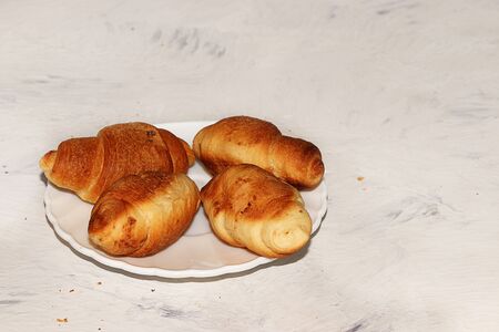 Four fresh ruddy croissants on a gray table with crumbs, place for text. Concept of a modern bakery. Delicious traditional breakfast.の写真素材