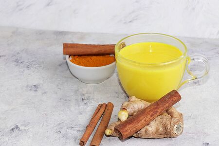 Healthy drink of golden turmeric latte with ginger root, cinnamon sticks, turmeric powder, spices for ayurvedic medicine. Alternative medicine concept, has a strong anti-inflammatory effect, detoxification of the body,の写真素材