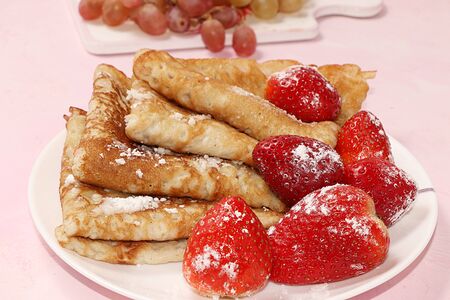 Pancakes with strawberries on a pink sunny background. The concept of healthy and natural food....