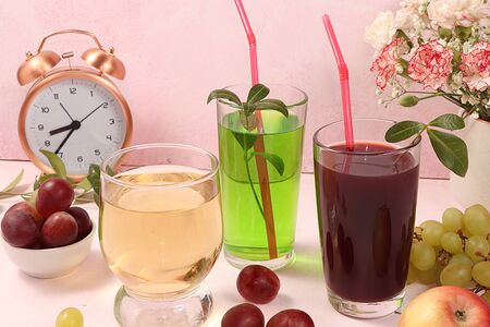 Fruit cocktail, cider, grape juices or fruit drinks in glasses and ingredients on a sunny table. The...