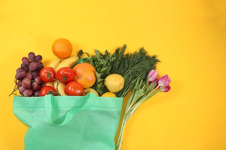 Healthy natural products in an eco bag on a bright background, the concept of a healthy lifestyle and weight loss, zero waste. Vegetables, fruits, apples and greens in cloth packaging, diet, body detox, flat lay. Banner for the screen and the store. No plastic.の写真素材