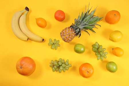 Summer banner, citrus fruits, grapefruit, orange, lemon, pineapple on a yellow background, pattern, minimal rest concept, diet, healthy food. Place for text flat layの写真素材