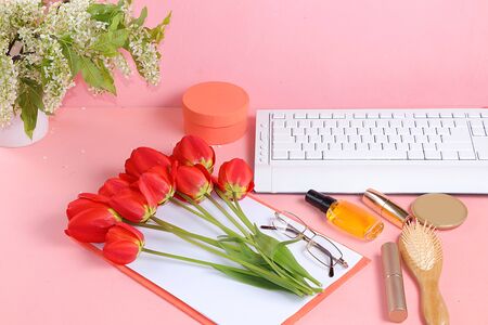 Work desk of a modern woman, home office. Notepad, tea, spring flowers and cosmetics on a light table. Minimal business concept,の写真素材