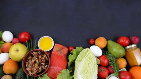 Vegetables, fruits and red fish on a dark background. The concept of healthy and natural food for weight loss, lifestyle, detox diet, keto diet, the purpose of which is to exclude carbohydrates, a place for text.の写真素材