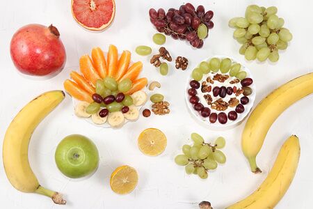 Healthy breakfast, food for children, yogurt with granola, oranges, banana and grapes on a light table. The concept of healthy and natural food, lifestyle.の写真素材