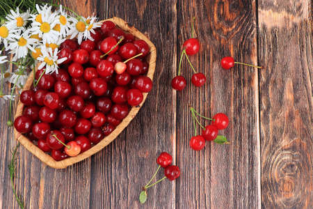 Fresh berries of cherries in a basket on a light table, top view, sweet cherry on a wooden light...