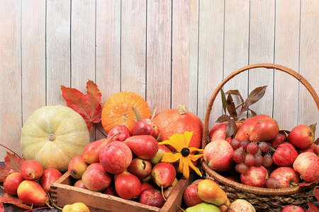 Autumn composition with seasonal pears, pumpkins, apples and flowers on a wooden background, Happy...