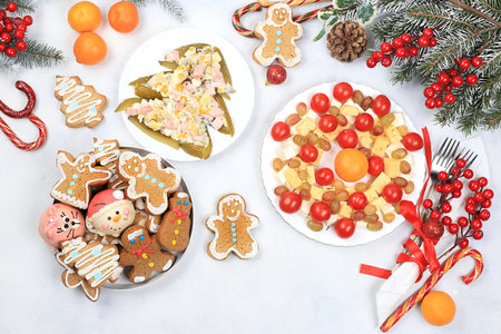 Christmas new year food, traditional festive salad olivier and cheese with tomatoes, grapes and gingerbread with fir branches and cones and decorations, dish design idea,の写真素材